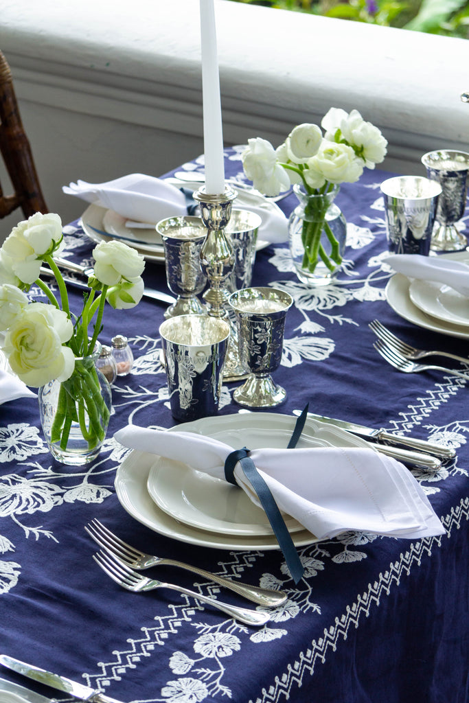 rectangular blue embroidered tablecloth with white flowers with place setting