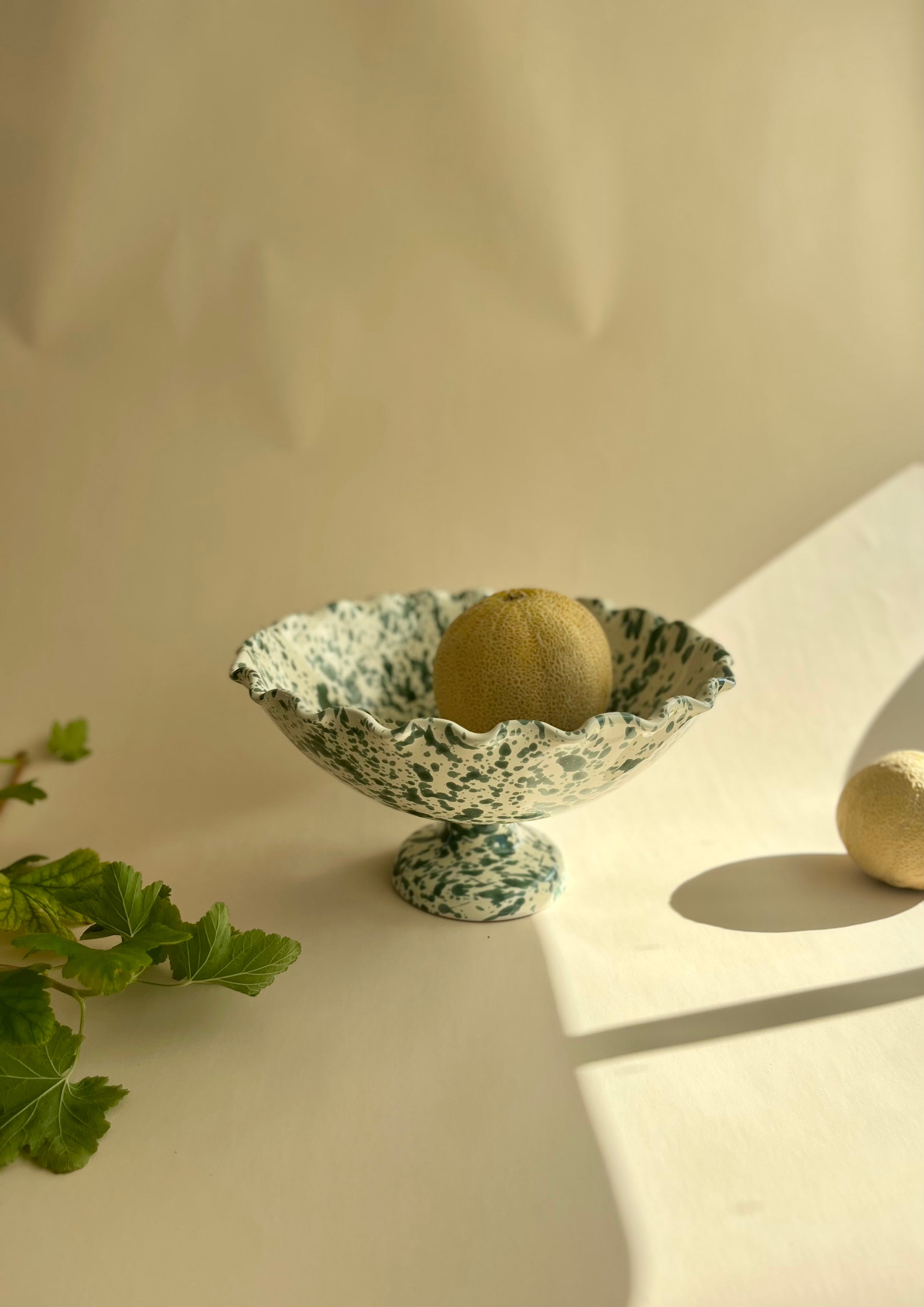 green and white spatterware compote bowl holding grapefruit