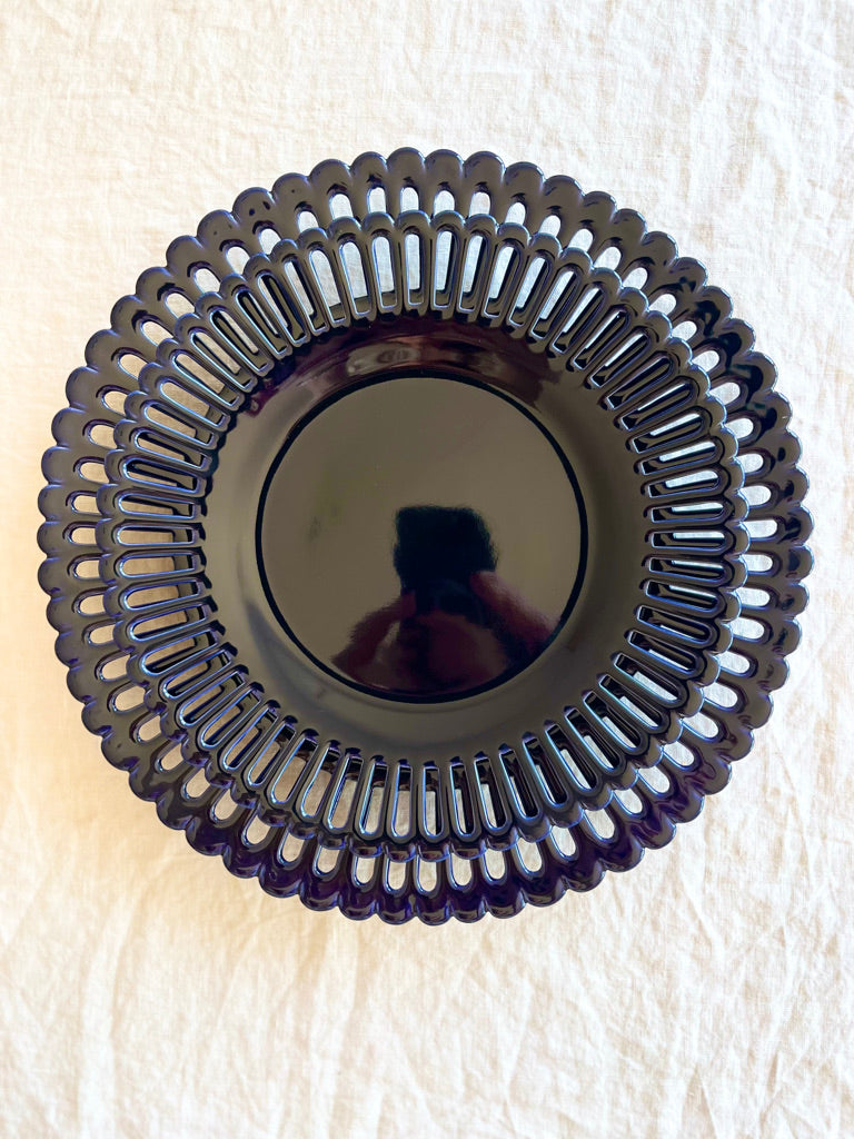 dark blue dinner plate with openwork rim and scalloped edge on white table