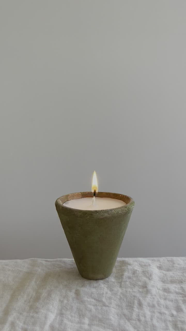 terra cotta candle with a mossy and aged green exterior video of candle on a table