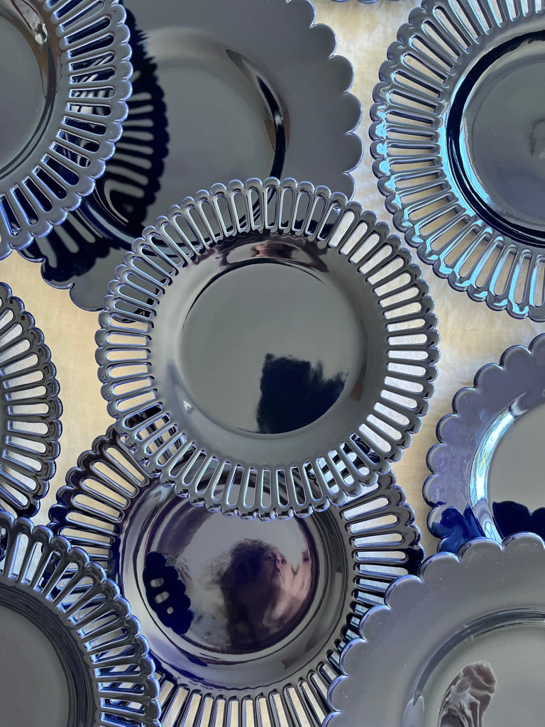 dark blue dinner plate with scalloped edge on white table