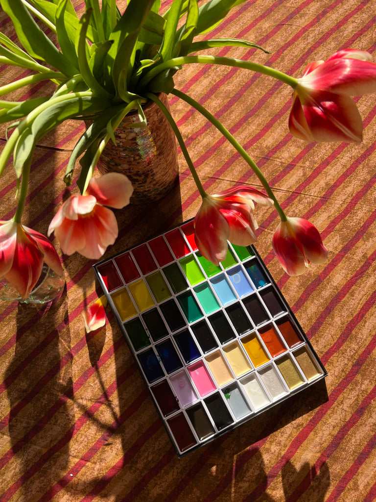 red and gold striped cotton tablecloth shown on a table with flowers