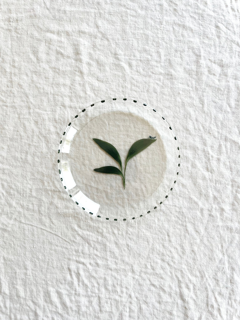 clear glass bread plate with hand painted green leaf with small ant on table