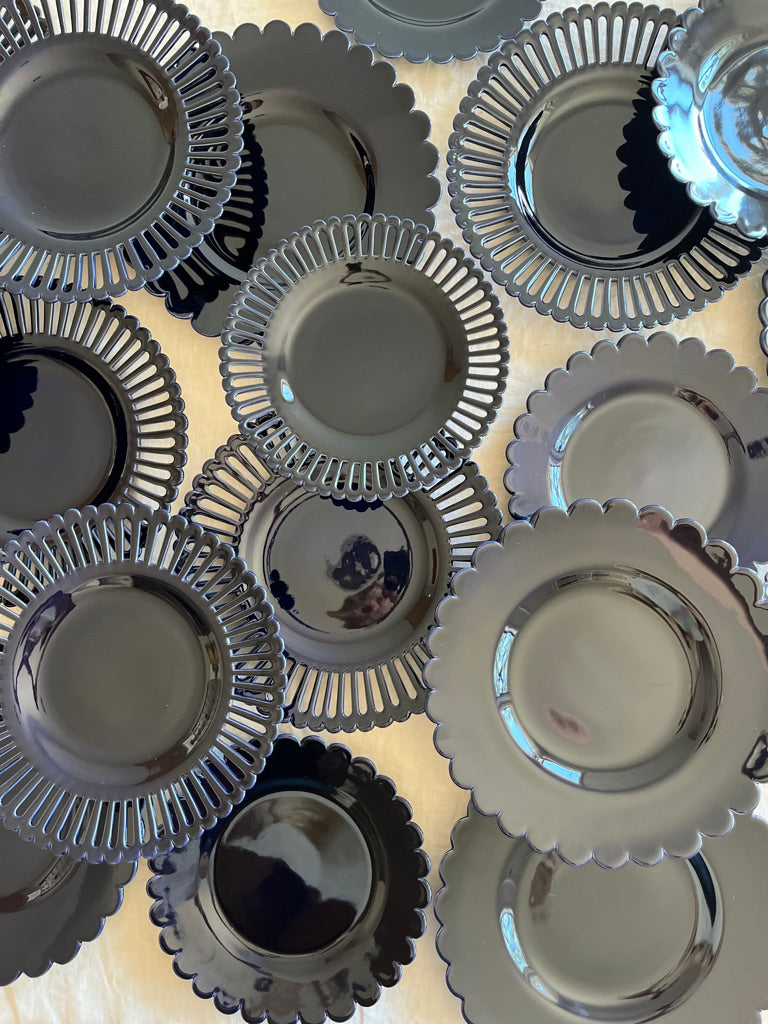 dark blue salad plate with openwork rim and scalloped edge on white table