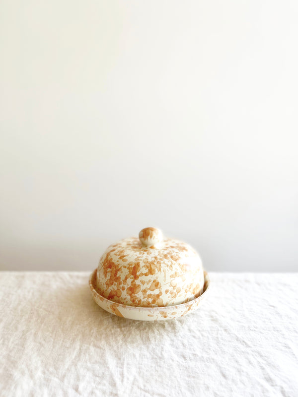 round white covered dish with tan speckled pattern