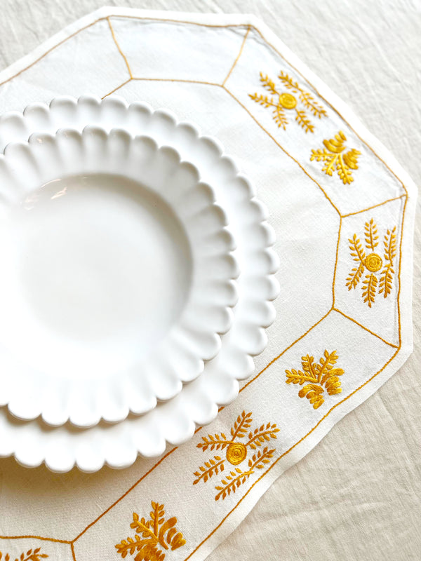 hand painted white dinner plate with scalloped edge on yellow placemat