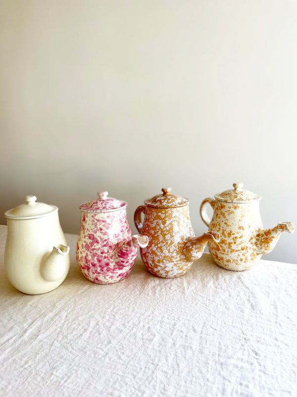 white coffee pot with pink speckled pattern in group of four