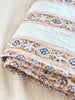 twin size white cotton quilt with gold, blue and pink floral stripes detail view
