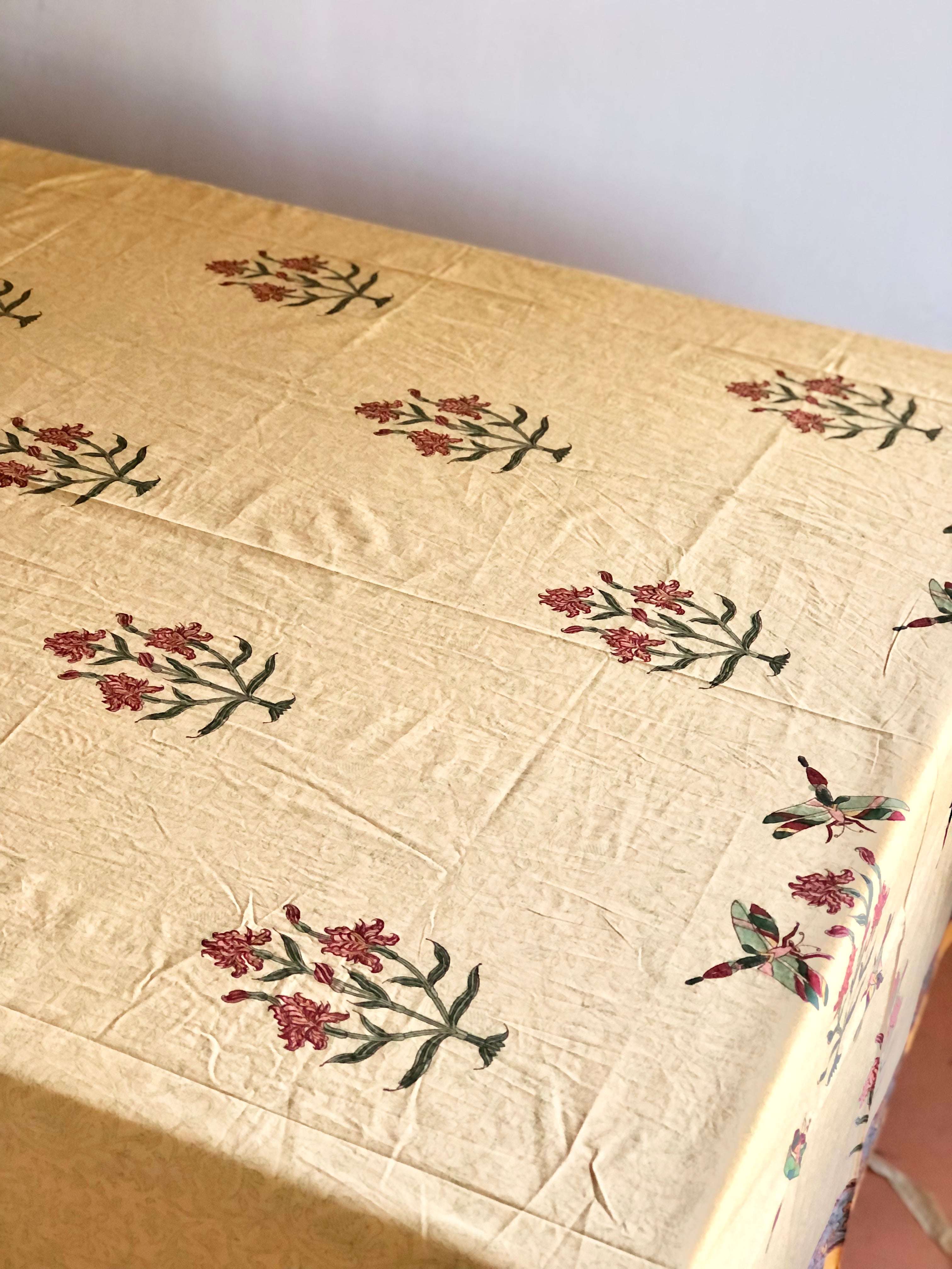 gold tablecloth with green dragonflies red irises and blue gray edge on table