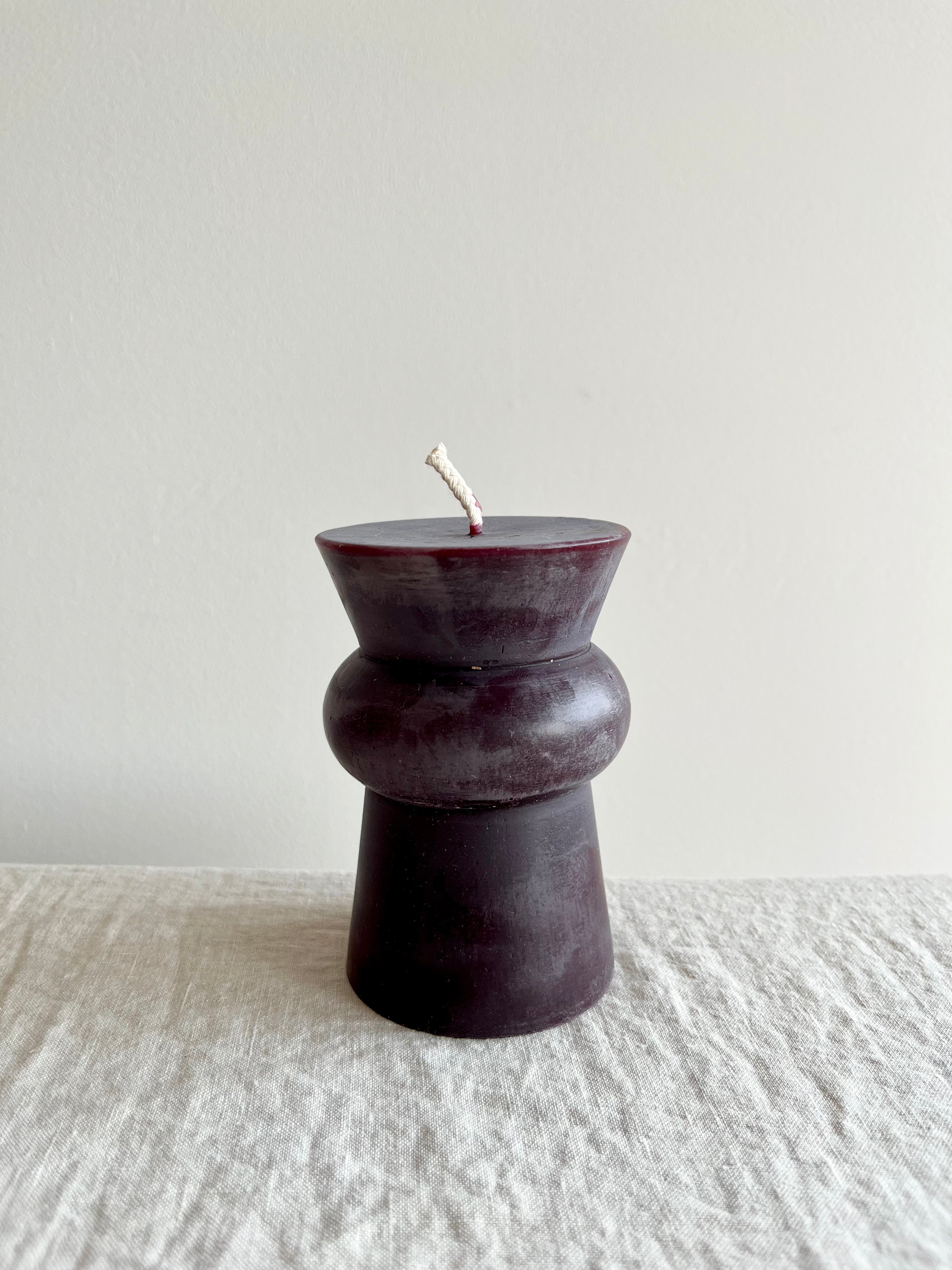 small wine colored totem candle on a table
