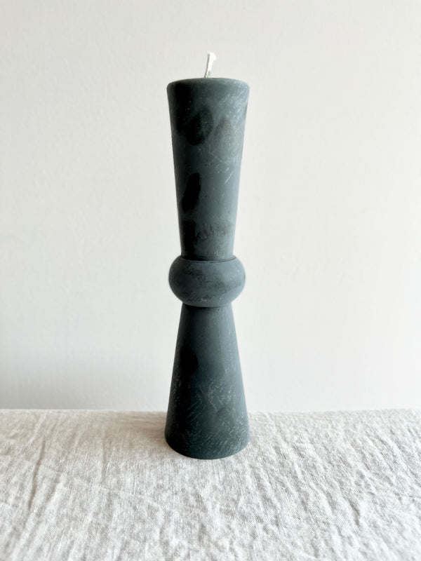 tall dark green totem candle on white table