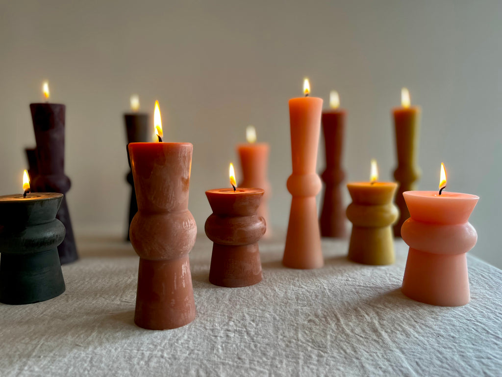 assorted totem candles with flame lit light pink wine and terra color