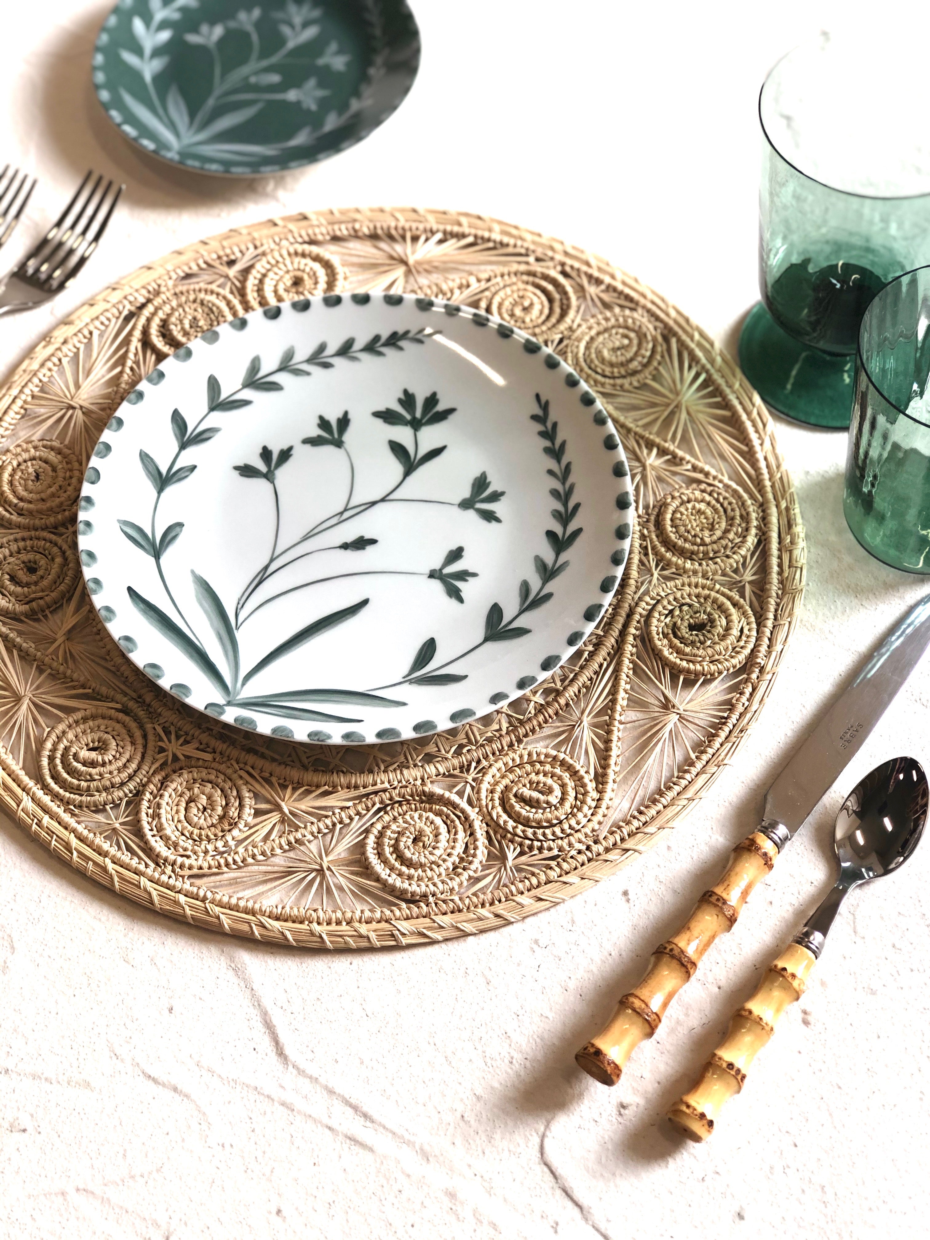 white salad plate with hand painted green floral design on woven placemat