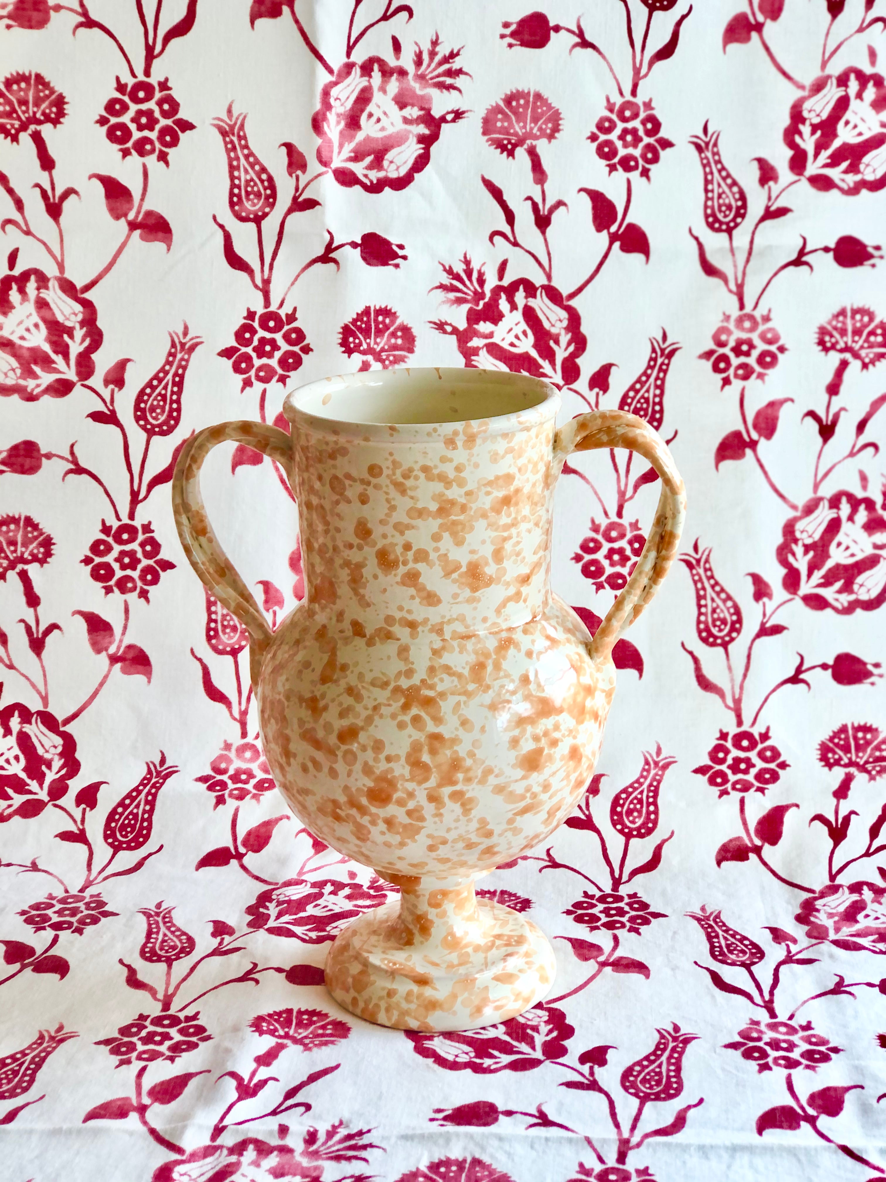 cream amphora vase with light brown speckle pattern 13 inches tall on red and white cloth