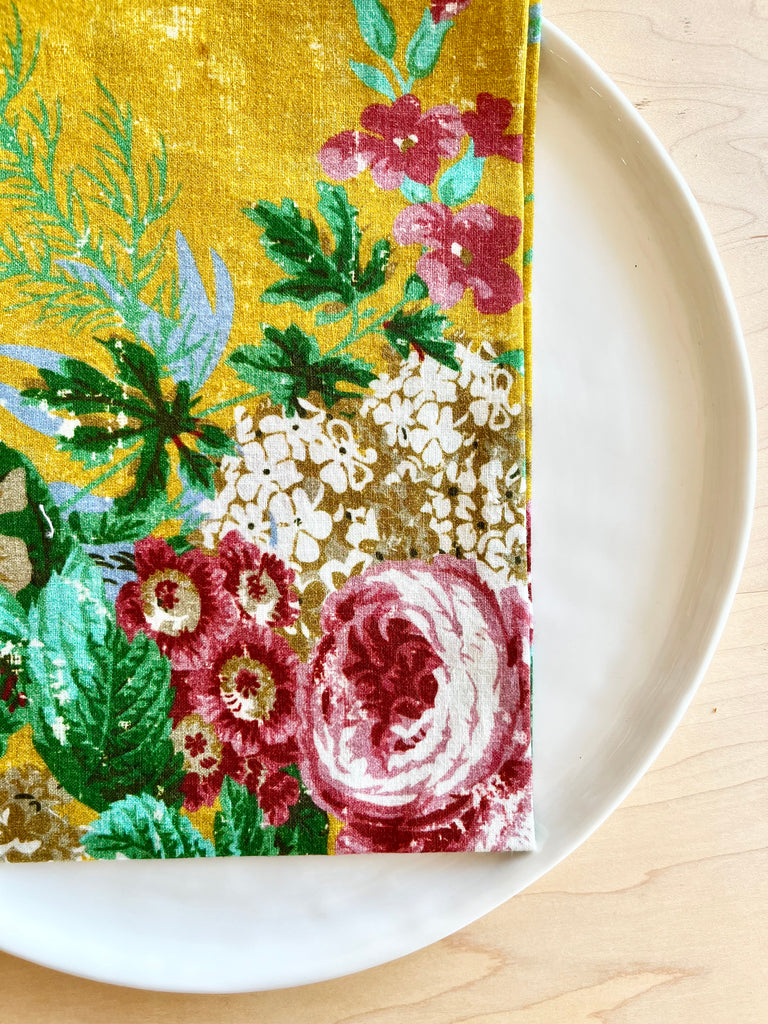 bright yellow cotton napkin with red floral print and light blue edge