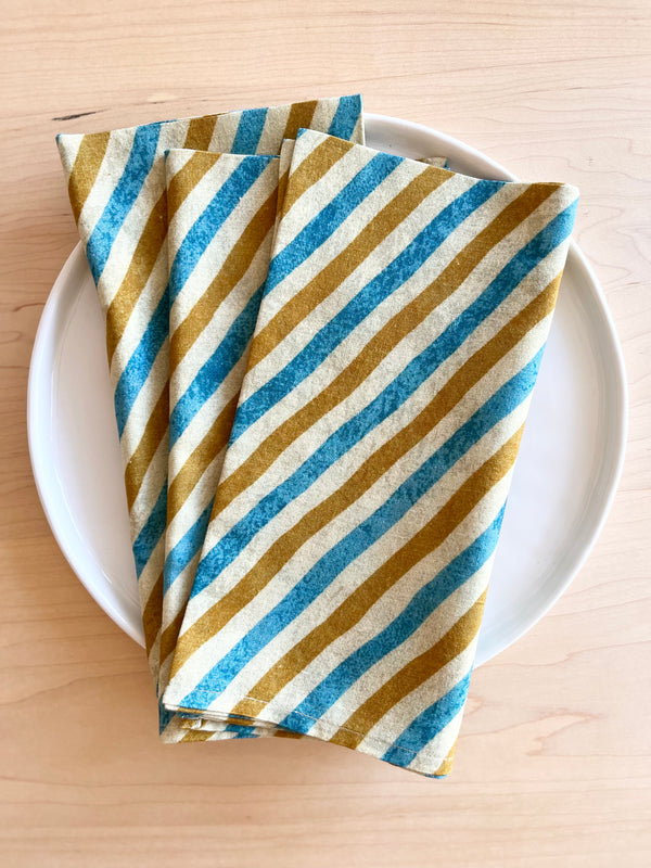 blue and gold cotton napkins 20 inch stacked on a plate