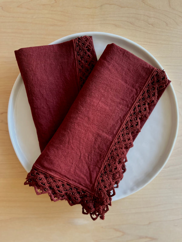 deep red linen napkins with macrame trim on plate