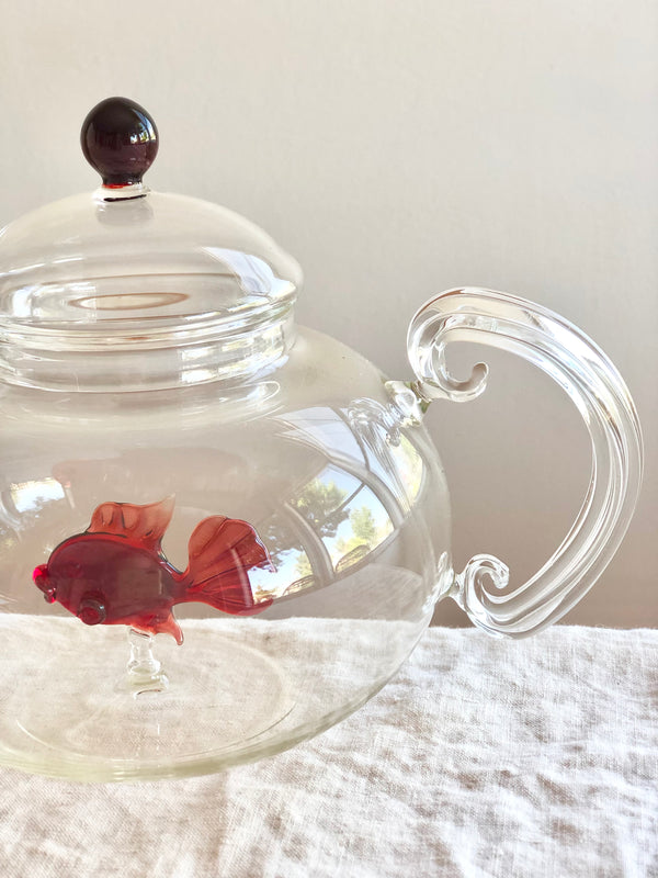 clear hand blown glass teapot with red glass fish in bottom detail view