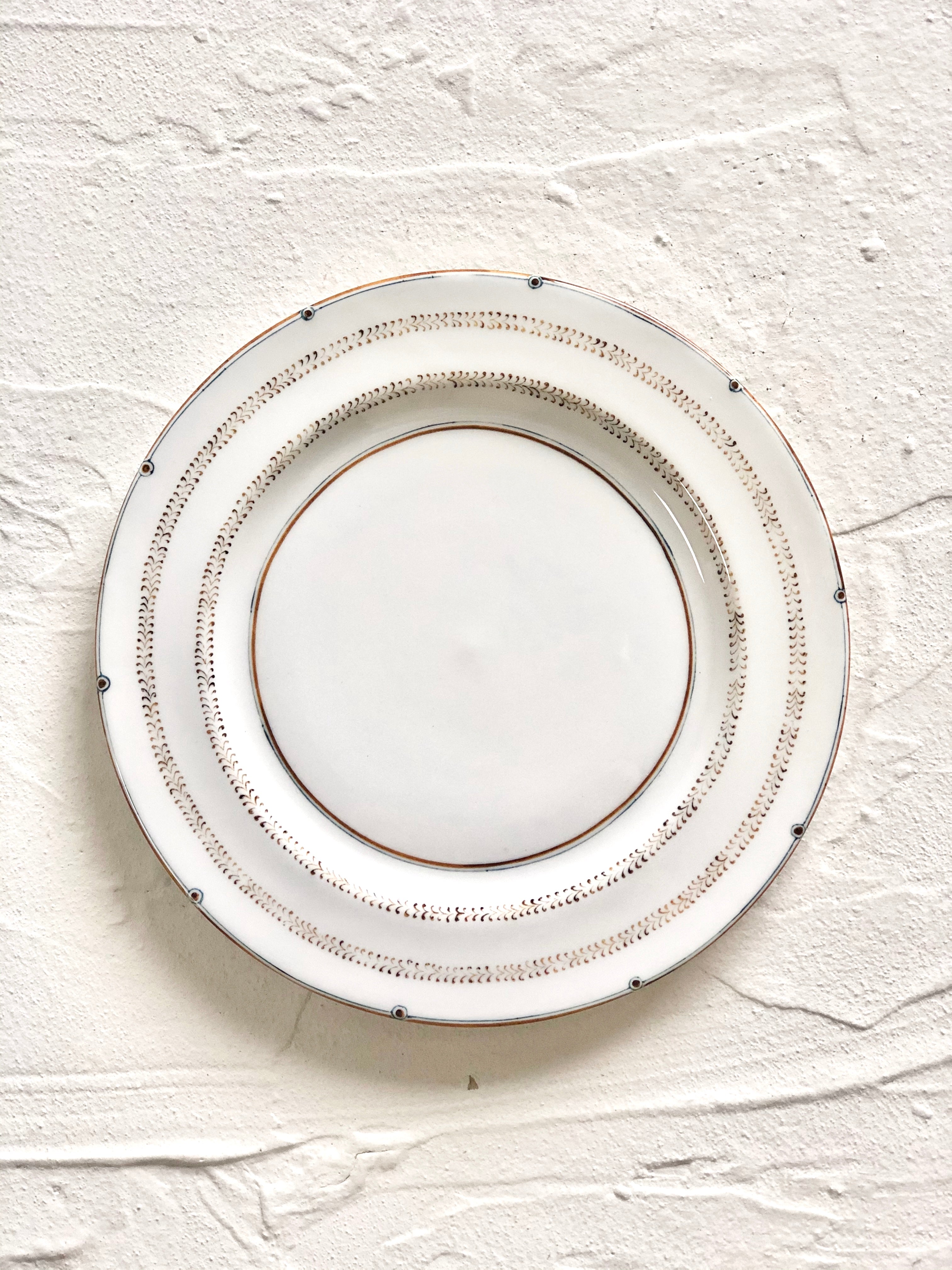 ceramic dinner plate with narrow brown brush strokes around rim on white table
