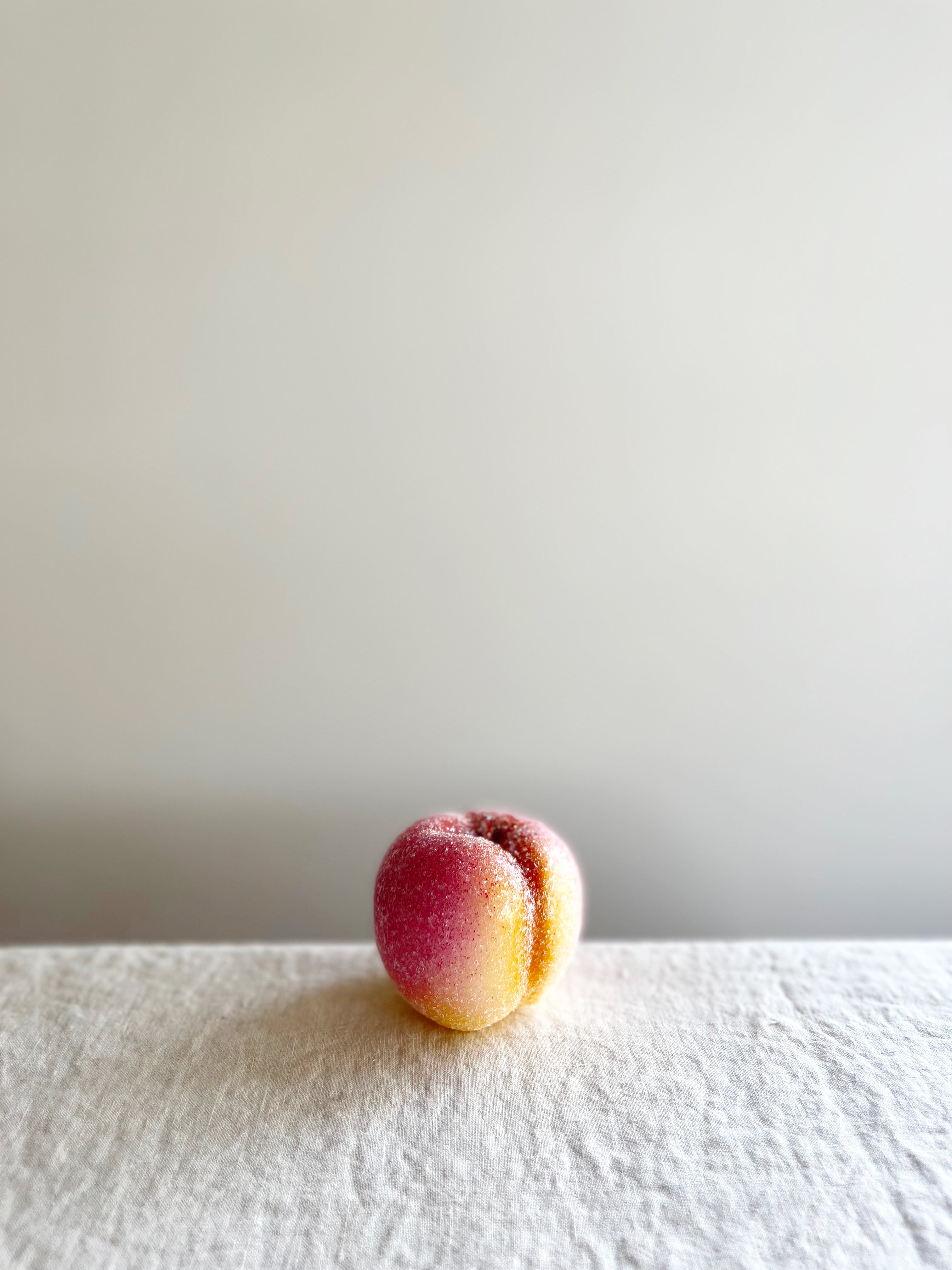 cereria introna sugared peach shaped paraffin candle on white table