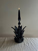 navy blue taper candle holder shaped like the top of a pineapple with lit blue candle
