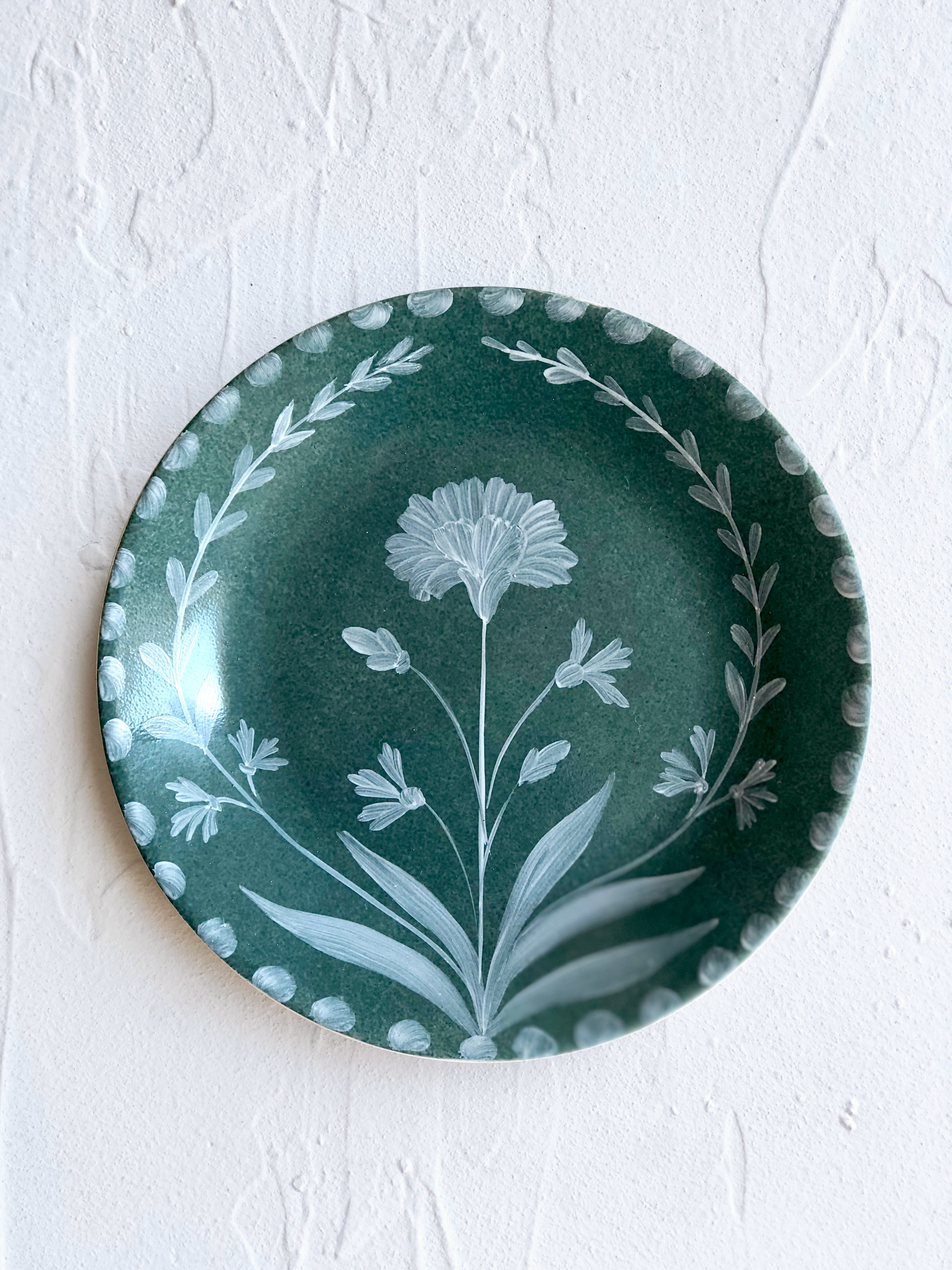 green dinner plate with hand painted white floral design detail view