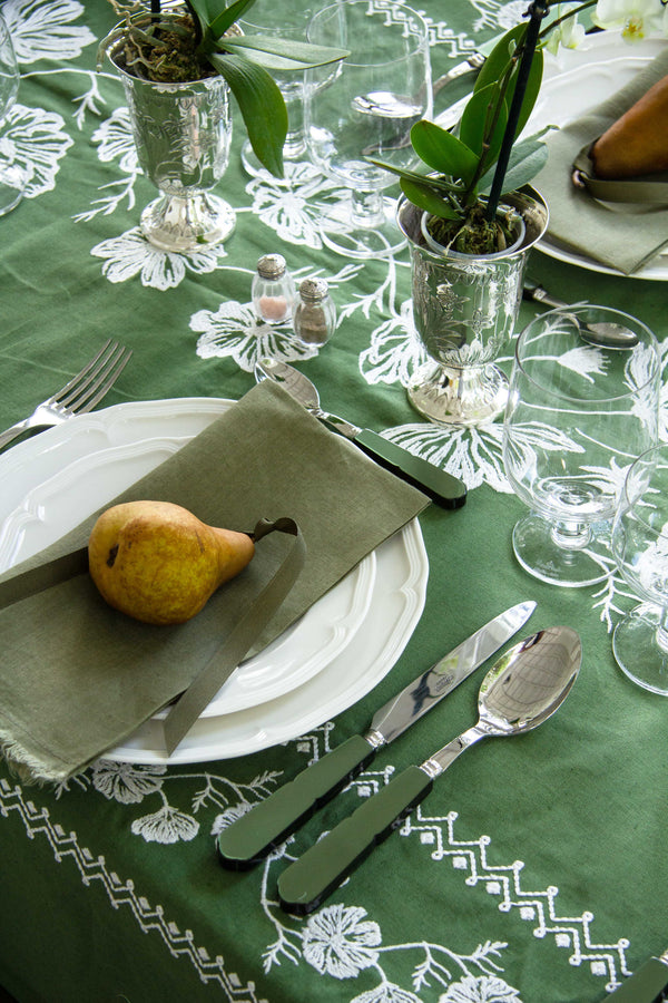 rectangular green embroidered tablecloth with white flowers with place setting
