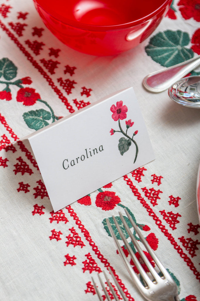 rectangular white embroidered tablecloth with red flowers with place card