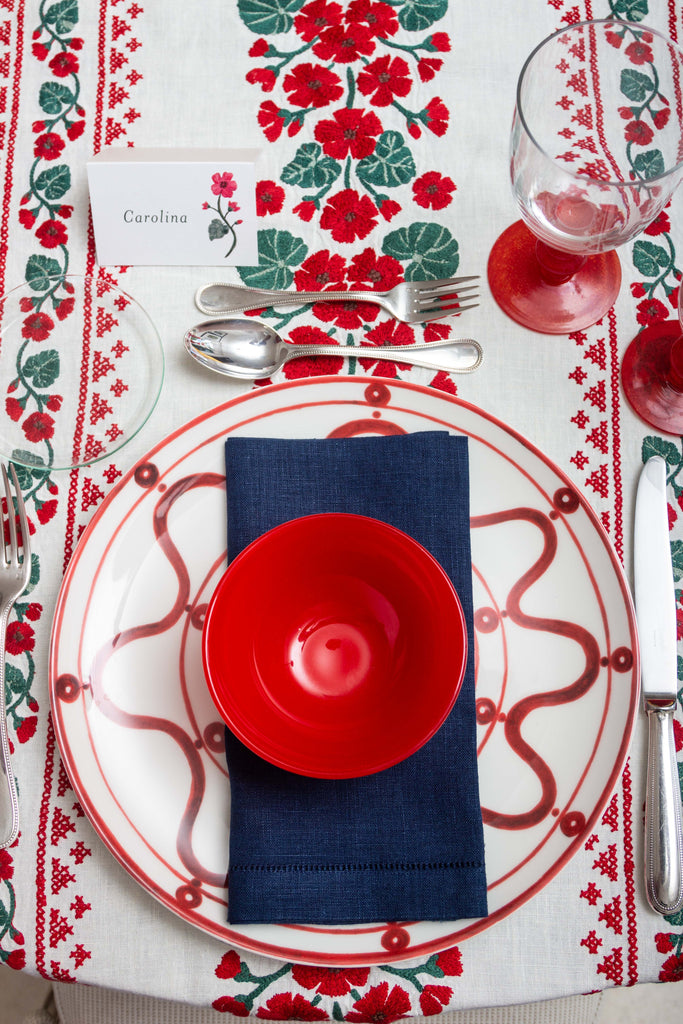 rectangular white embroidered tablecloth with red flowers with red dishes