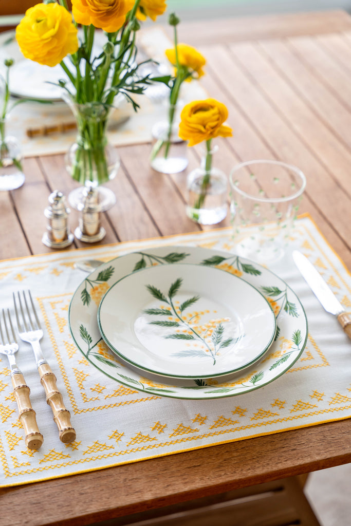 rectangular ivory and yellow embroidered placemat on wooden table
