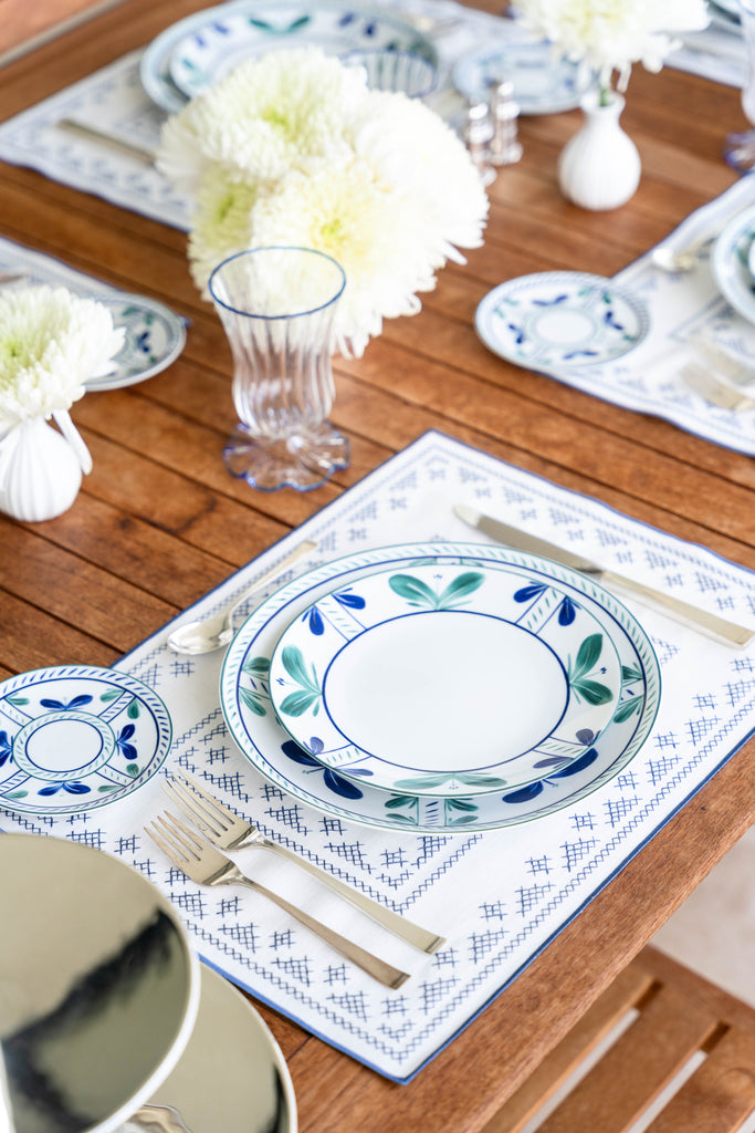 rectangular ivory and blue embroidered placemat on wooden table
