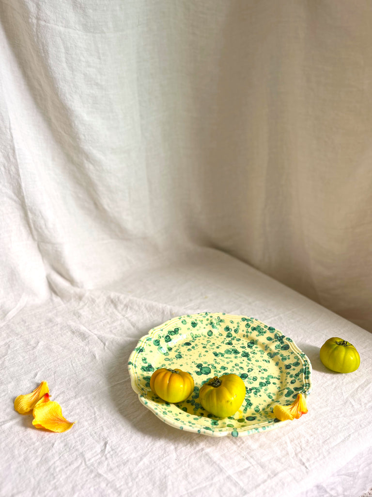 green and cream round spatterware platter on white cloth