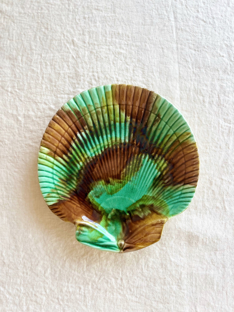 green and brown shell shaped majolica plate on table
