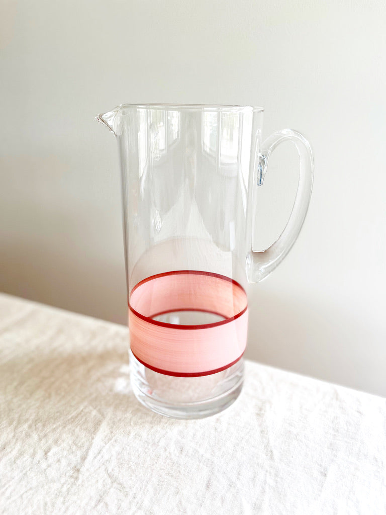 glass pitcher with hand painted pink and red stripes 10 inches tall on white table