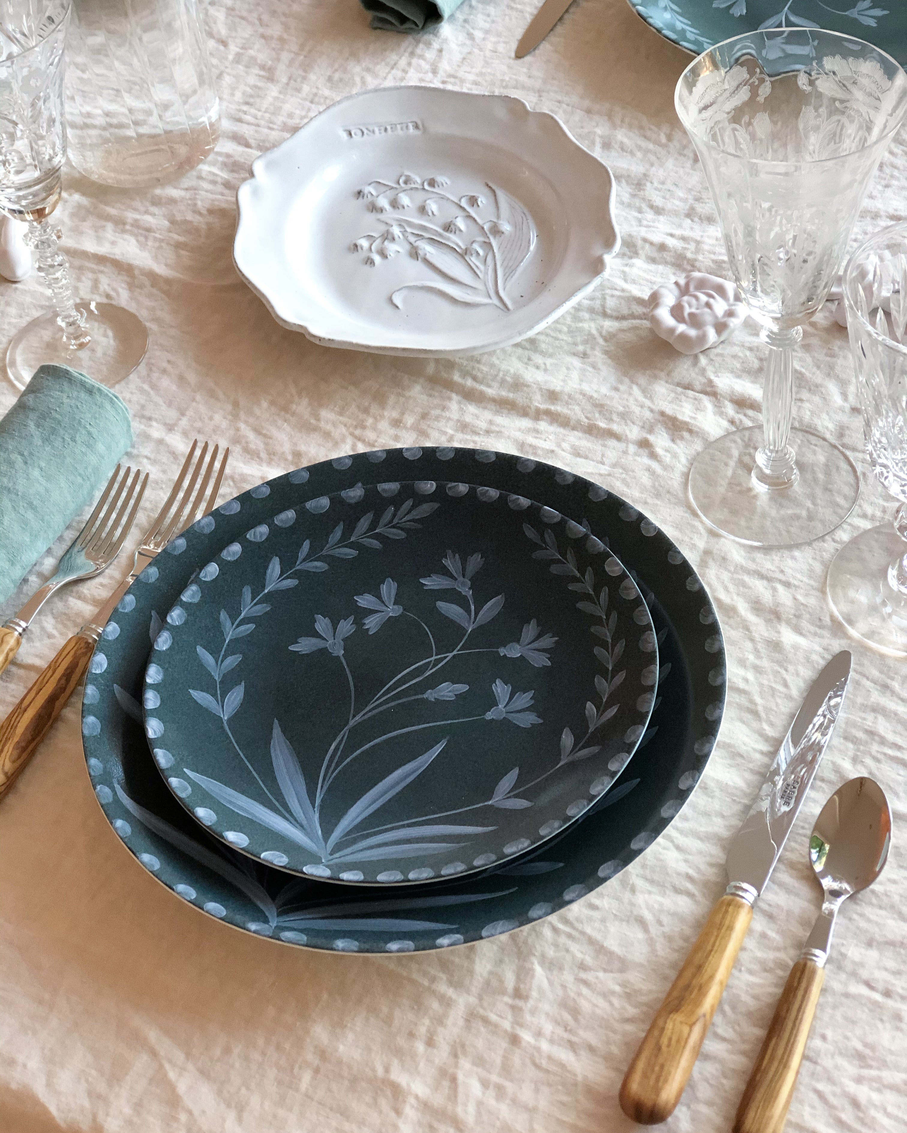 cream linen tablecloth with macrame trim with dark green plate