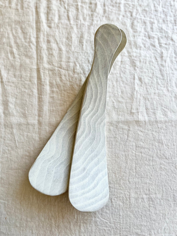 salad servers made of maplewood on white table