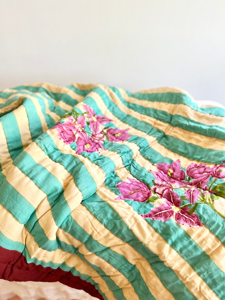 green striped cotton quilt with bougainvillea in center close up