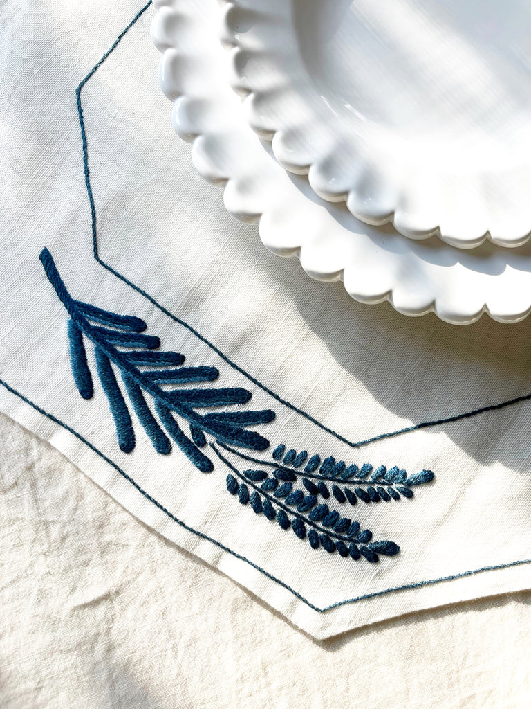 Octagonal dark blue embroidered white linen placemat close up