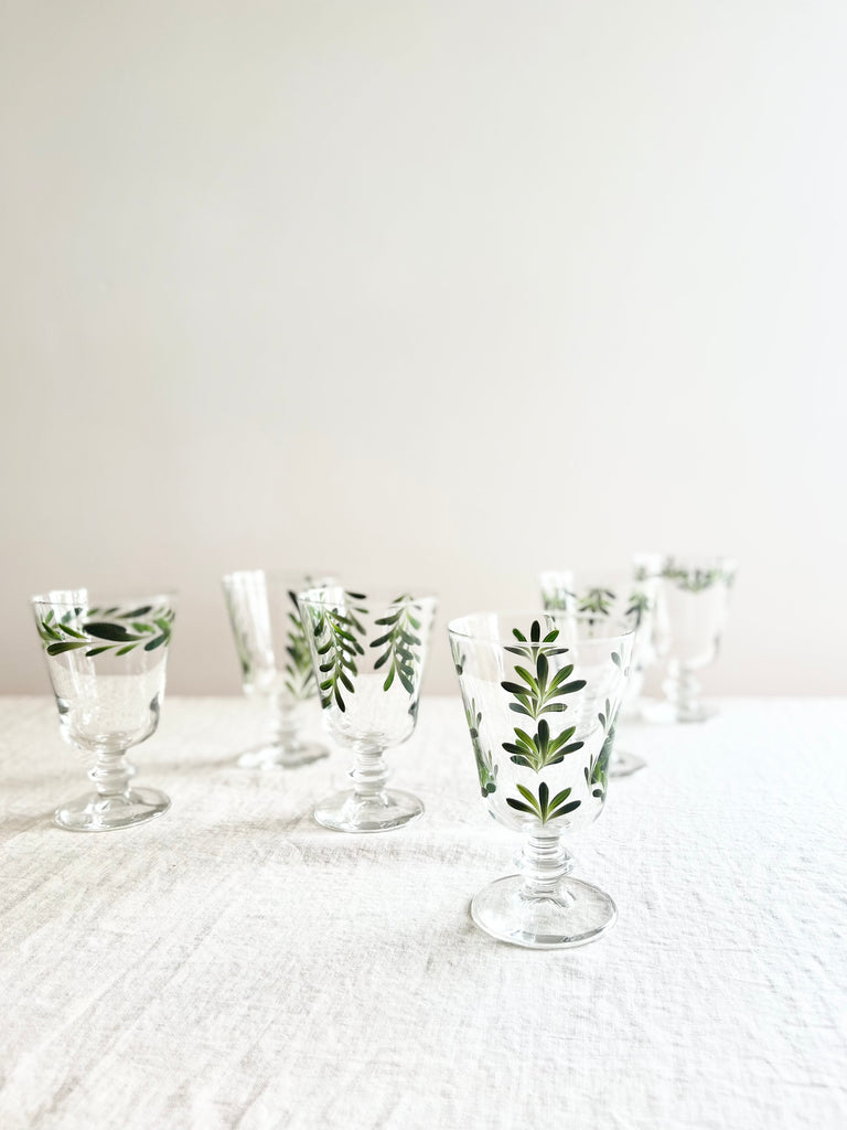 hand painted wine glasses with dark green leaf pattern on white table
