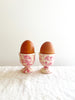 cream egg cups with pink splatter pattern 2 inches in diameter holding eggs