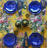 yellow tablecloth with pink white and blue floral pattern with blue plates