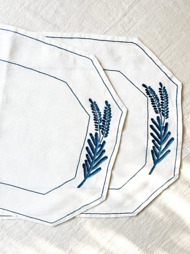 Octagonal dark blue embroidered white linen placemats