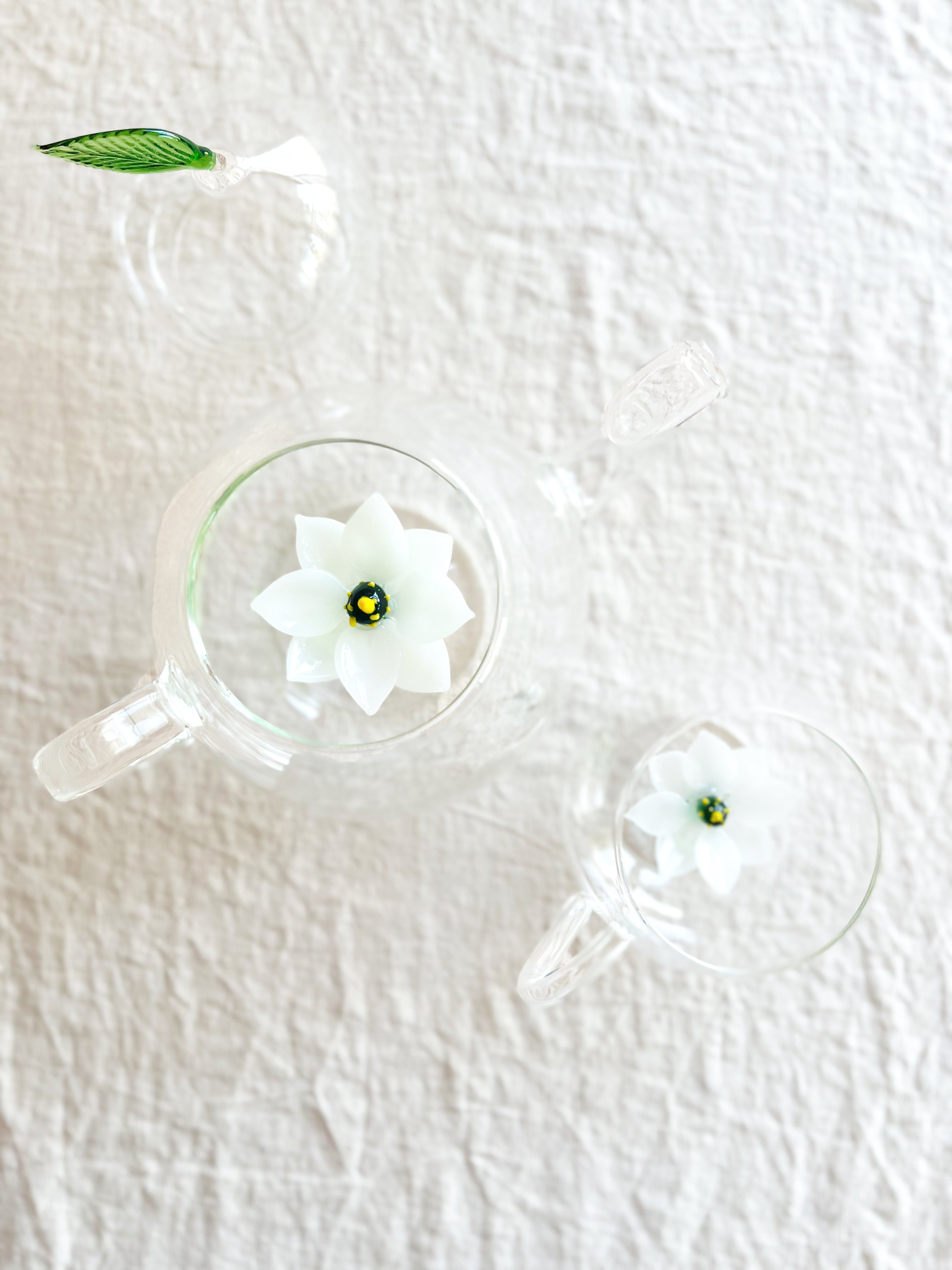 clear hand blown glass teapot with white glass lotus flower in bottom top view