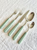 sabre stainless steel flatware set with sage green resin handle on white table