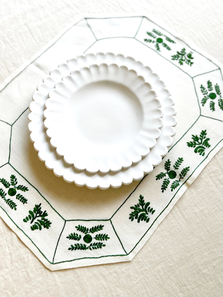 octagonal white linen placemat with olive green embroidery 19.5" by 16" with white plates