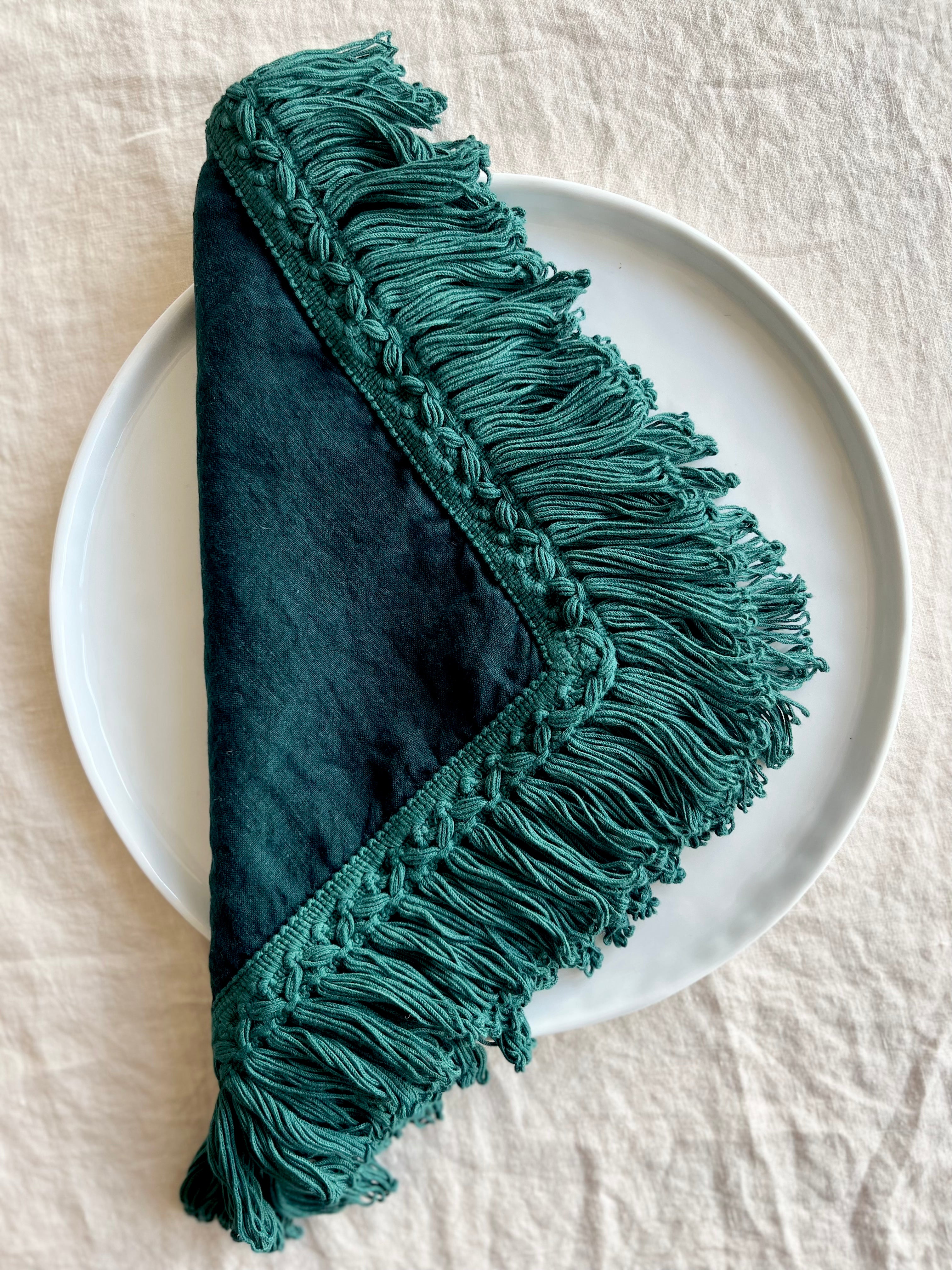 teal linen napkins with fringe on white plate