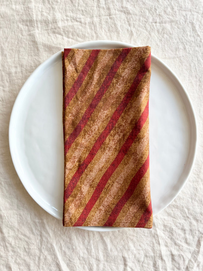 red gold and tan striped cotton napkin on plate