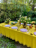 Yellow Milano Macrame Tablecloth shown on a table outside with settings