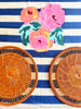 round placemat woven in tangerine color on blue striped cloth