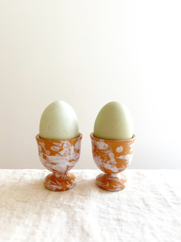 fasano egg cups with splatter pattern in sienna holding eggs